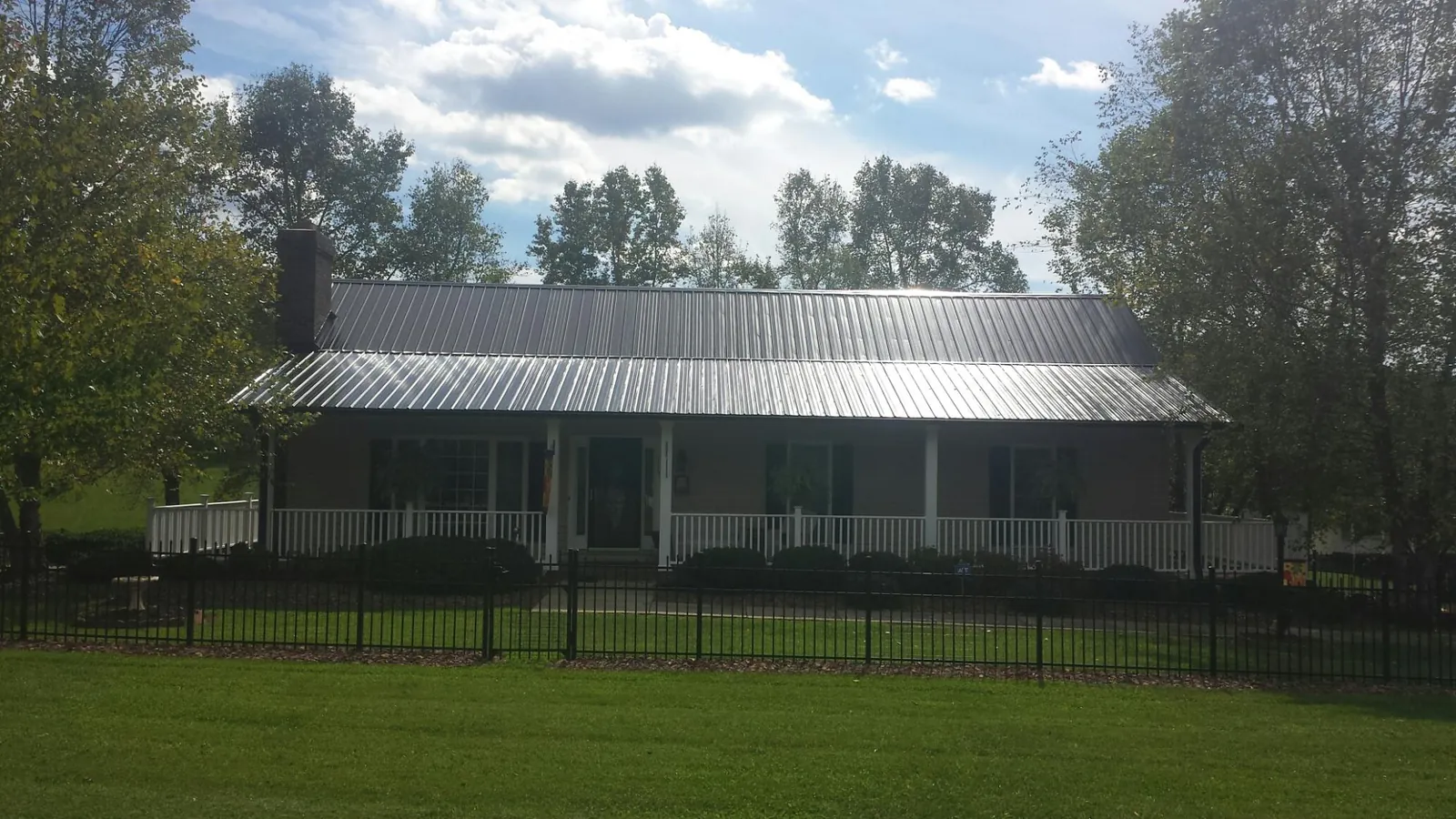 Gray metal roof on a brick ranch with a full width front porch — Gutter Guard Installation work by our crew in Grass Lake