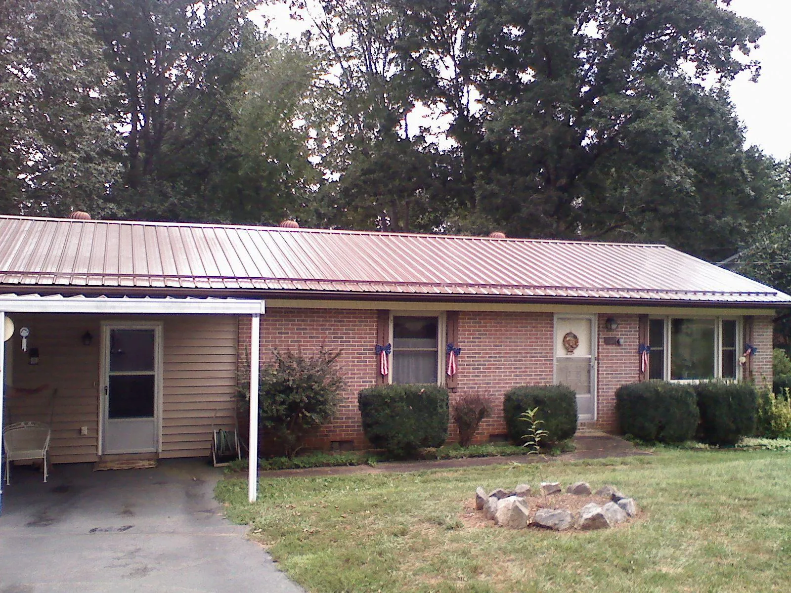 Bronze metal roof and carport on a brick ranch home — Roof Repair work by our crew in Grass Lake