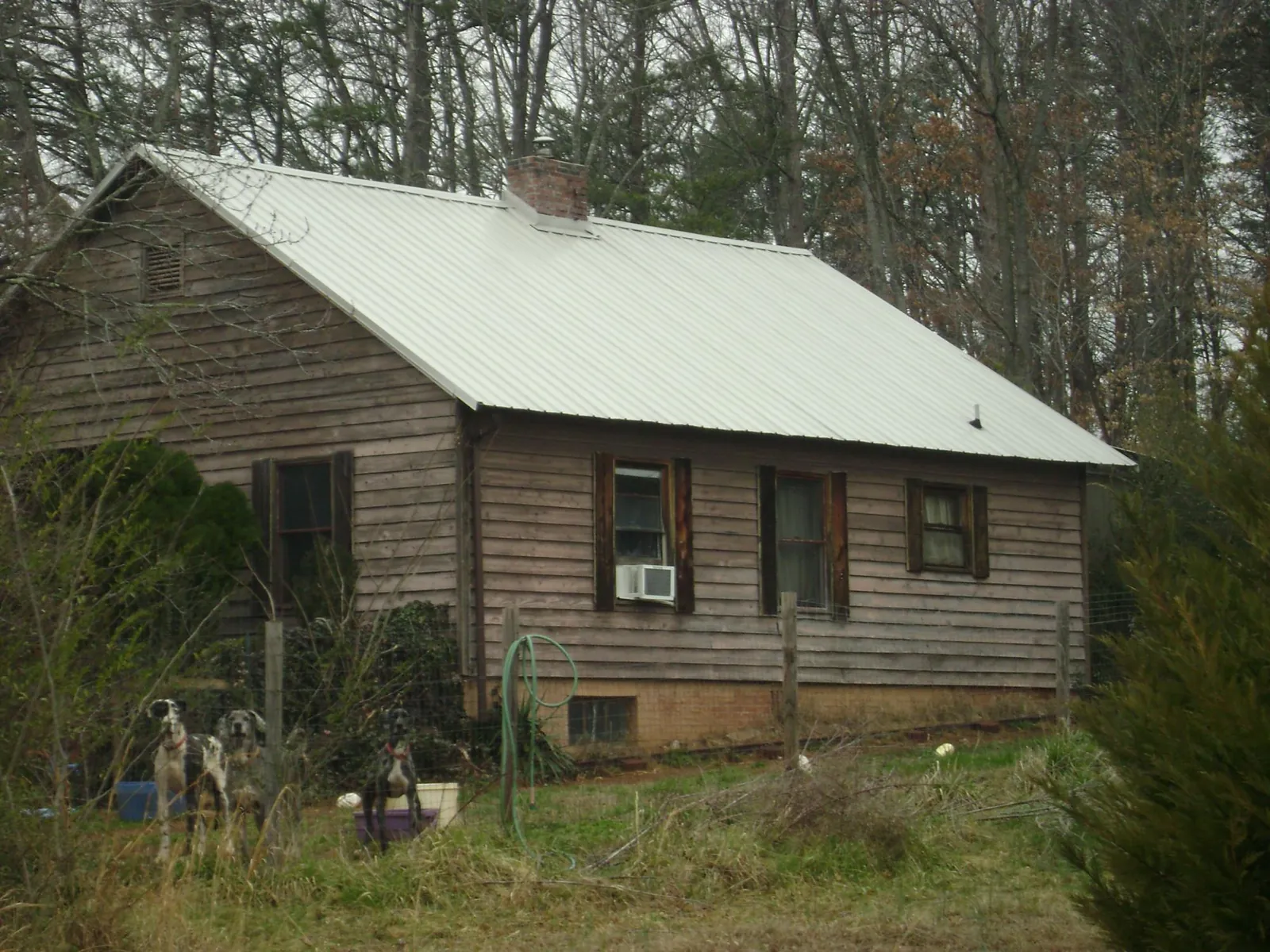 White metal roof on an old wood sided farmhouse, from a Metal Roof Installation job in Grass Lake