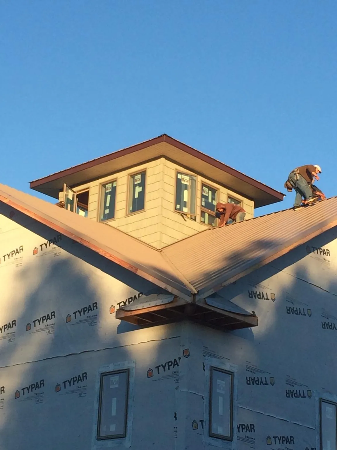Roofers working around a rooftop cupola on a new metal roof at sunset — Roof Waterproofing in Grass Lake by Roofing Brothers